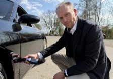 Kfz-Sachverständiger Andreas Anzer begutachtet einen Unfallschaden an der Fahrzeugtür eines schwarzen Porsches– mit Prüfung der lackzusammensetzung